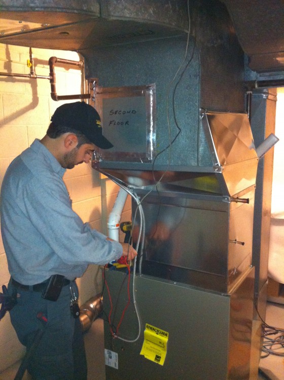 1 man wearing hat, working on furnace, in basement